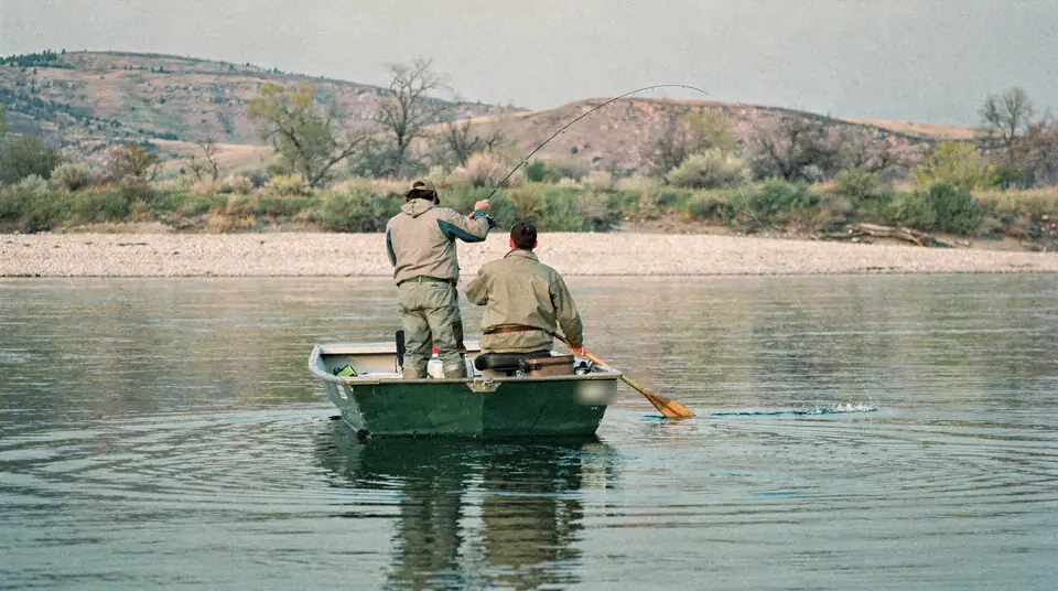 Two anglers seen from behind in a drift boat on a calm river
